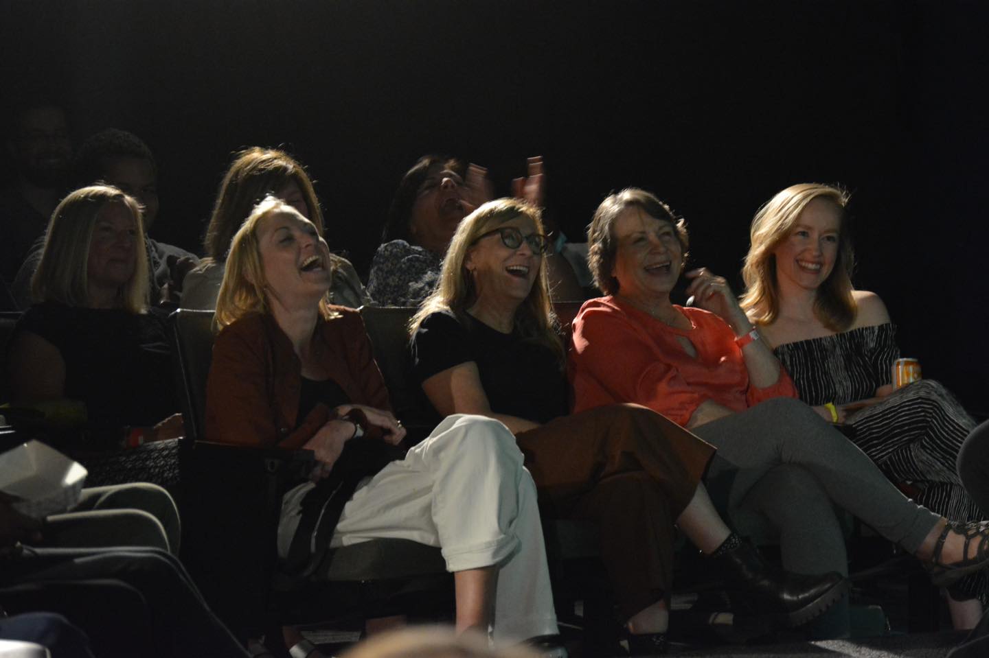 Women watching a comedy show and laughing. They are enjoying the show.